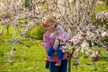 Çiçek açan bir parkta kollarında güzel bir kız.
