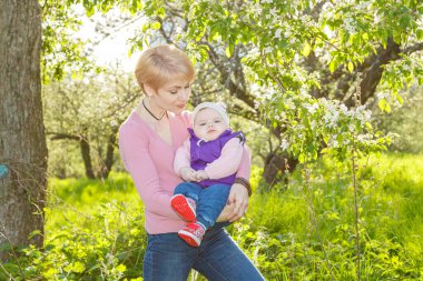 Çiçek açan bir parkta kollarında güzel bir kız.