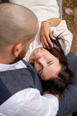 beautiful girl in a white dress and a guy are sitting on a bench close-up