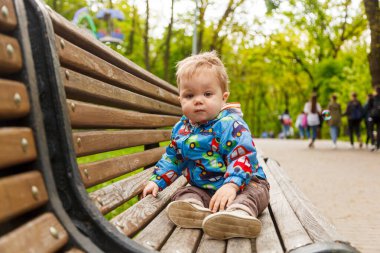 Parkta bir bankta sabun köpüğü yakalayan küçük bir çocuğun portresi.