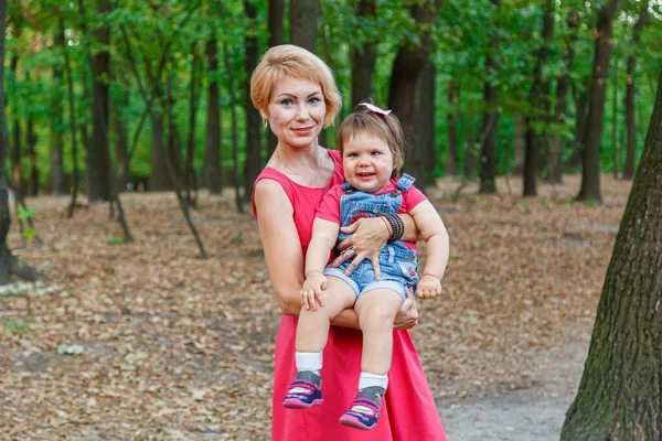 Güzel anne kızıyla birlikte yazın parkta yürür.