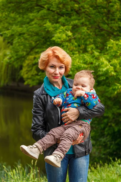 Parkta bir çocukla güzel bir kız gölün arka planında yakın planda.