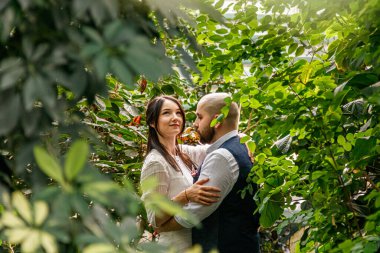 Parkta, tropikal ağaçların arasında güzel bir çift kız ve erkek.