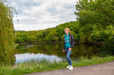 Parktaki güzel kız göl parkının arka planında yakın planda.