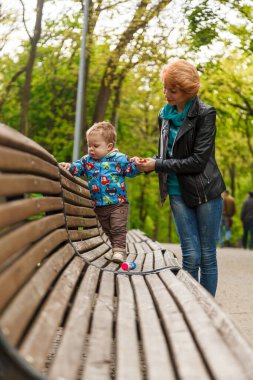 beautiful girl (mother) with a boy (son) in the park in the park are sitting on a bench with a close-up