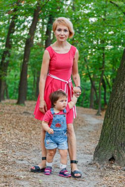 Güzel anne kızıyla birlikte yazın parkta yürür.