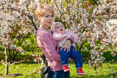 Çiçek açan bir parkta kollarında güzel bir kız.