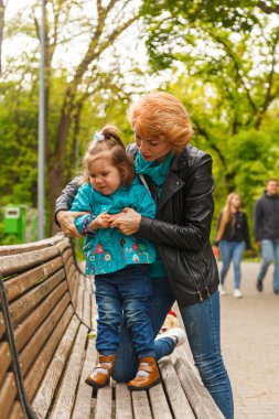 Parktaki parkta bir kızla güzel bir kız (anne) yakın plan bir bankta oturuyorlar.