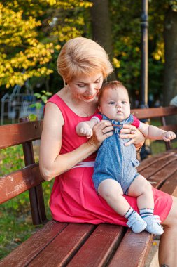 beautiful mother with her daughter and son are sitting on a bench in the park in the summer close-up