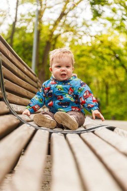 Parkta bir bankta sabun köpüğü yakalayan küçük bir çocuğun portresi.
