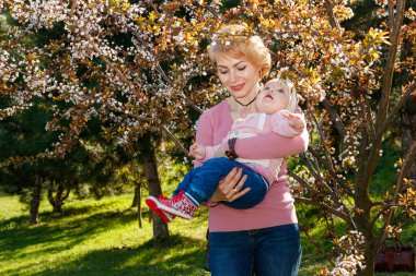Çiçek açan bir parkta kollarında güzel bir kız.
