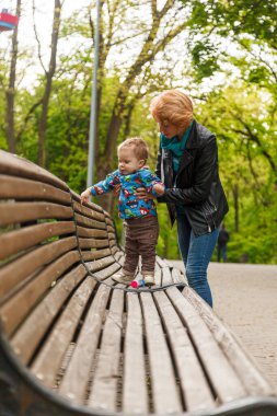 Parktaki parkta bir oğlanla güzel bir kız (anne) yakın plan bir bankta oturuyor.