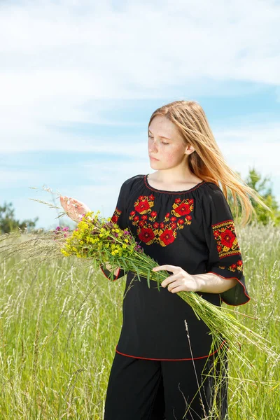 美しいです女の子で黒Vyshyvankaで花でフィールドを見下ろす空のクローズアップ — ストック写真
