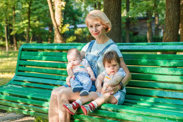 Çocuklu güzel bir kız parktaki bankta oturuyor.