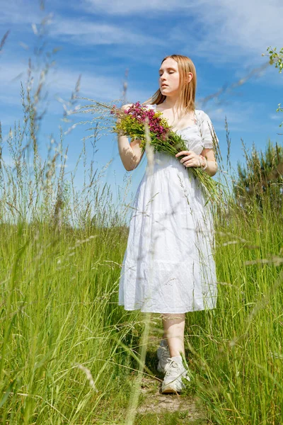 白いドレスに花のある美しい女の子が空を見下ろすフィールドでクローズアップ — ストック写真