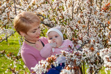 Çiçek açan bir parkta kollarında güzel bir kız.