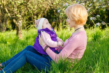 Çiçek açan bir parkta kollarında güzel bir kız.