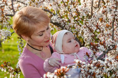 Çiçek açan bir parkta kollarında güzel bir kız.