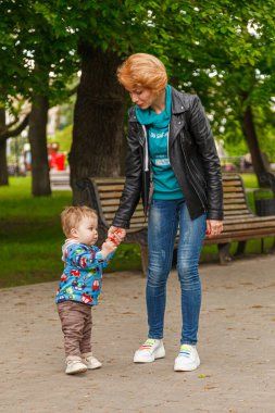 Parktaki parkta bir oğlanla güzel bir kız (anne) yakın plan bir bankta oturuyor.