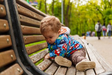 Parkta bir bankta sabun köpüğü yakalayan küçük bir çocuğun portresi.
