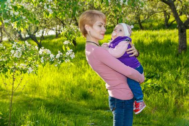 Çiçek açan bir parkta kollarında güzel bir kız.