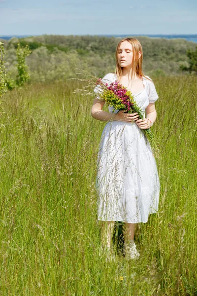白いドレスに花のある美しい女の子が空を見下ろすフィールドでクローズアップ — ストック写真