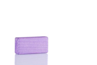 Wooden cube of purple color on a white background close up