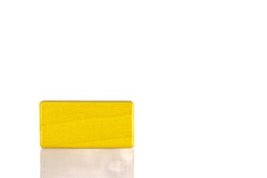 Wooden cube of yellow color on a white background close-up