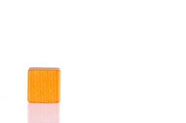 Wooden cube of orange color on a white background close-up