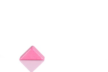 Wooden triangle of pink color on a white background close-up