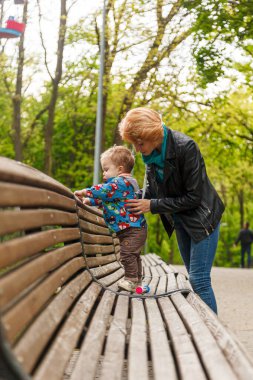 Parktaki parkta bir oğlanla güzel bir kız (anne) yakın plan bir bankta oturuyor.