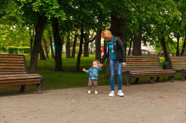 Parktaki parkta bir oğlanla güzel bir kız (anne) yakın plan bir bankta oturuyor.