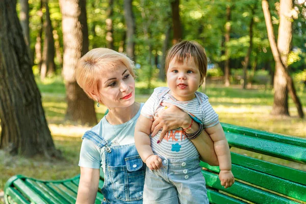 Çocuklu güzel bir kız parktaki bankta oturuyor.