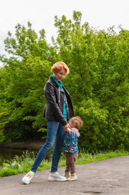 Parkta bir çocukla güzel bir kız gölün arka planında yakın planda.