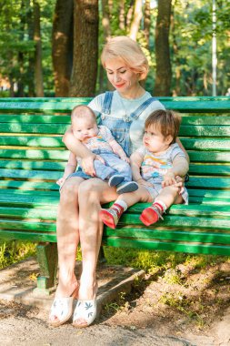 Çocuklu güzel bir kız parktaki bankta oturuyor.