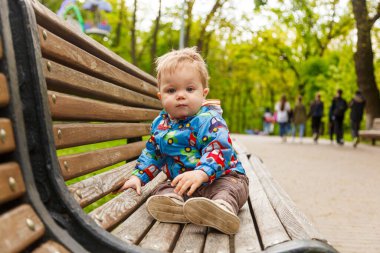 Parkta bir bankta sabun köpüğü yakalayan küçük bir çocuğun portresi.