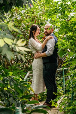 Parkta, tropikal ağaçların arasında güzel bir çift kız ve erkek.