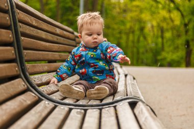 Parkta bir bankta sabun köpüğü yakalayan küçük bir çocuğun portresi.