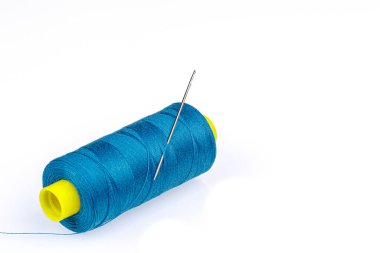 Beyaz arka planda iğnesi olan mavi iplikli makro skein.