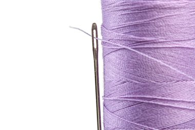 Beyaz arka plan üzerinde bir iğne ile iplik mor renkleri makro skein yakın plan