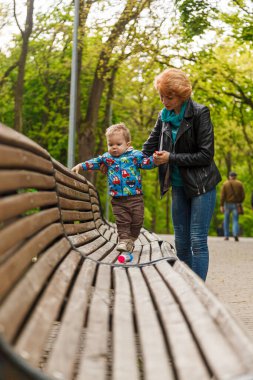 Parktaki parkta bir oğlanla güzel bir kız (anne) yakın plan bir bankta oturuyor.