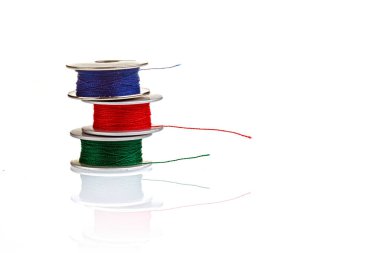 Beyaz arkaplanda mavi, kırmızı, yeşil renkli iplik makaraları