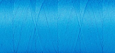 Beyaz arkaplanda mavi renkli bir makara içerisindeki ipliklerin dokusu