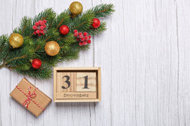 Noel ağacı dalında oyuncaklar, hediyeler ve ahşap takvimle 31 Aralık 'ta ahşap bir arka planda.