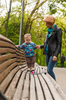 beautiful girl (mother) with a boy (son) in the park in the park are sitting on a bench with a close-up