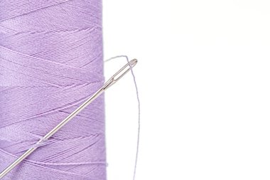 Beyaz arka plan üzerinde bir iğne ile iplik mor renkleri makro skein yakın plan