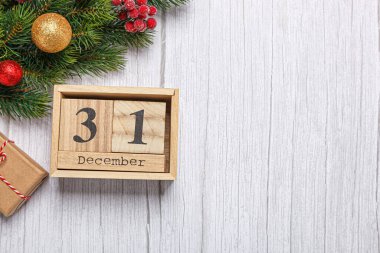 Noel ağacı dalında oyuncaklar, hediyeler ve ahşap takvimle 31 Aralık 'ta ahşap bir arka planda.