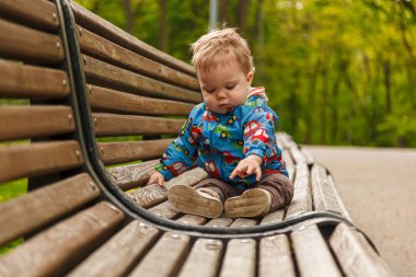 Parkta bir bankta sabun köpüğü yakalayan küçük bir çocuğun portresi.