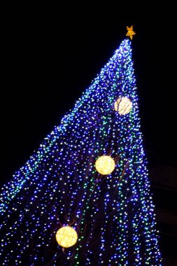 Gece gökyüzünde simsiyah bir arka planda şık ışıklar ve Noel ağacı