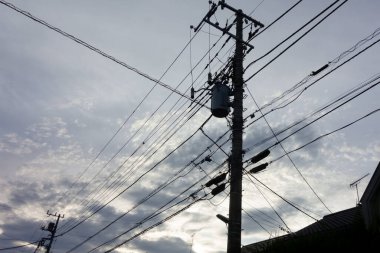 Summer twilight evening, high-voltage towers as silhouettes, power transmission equipment